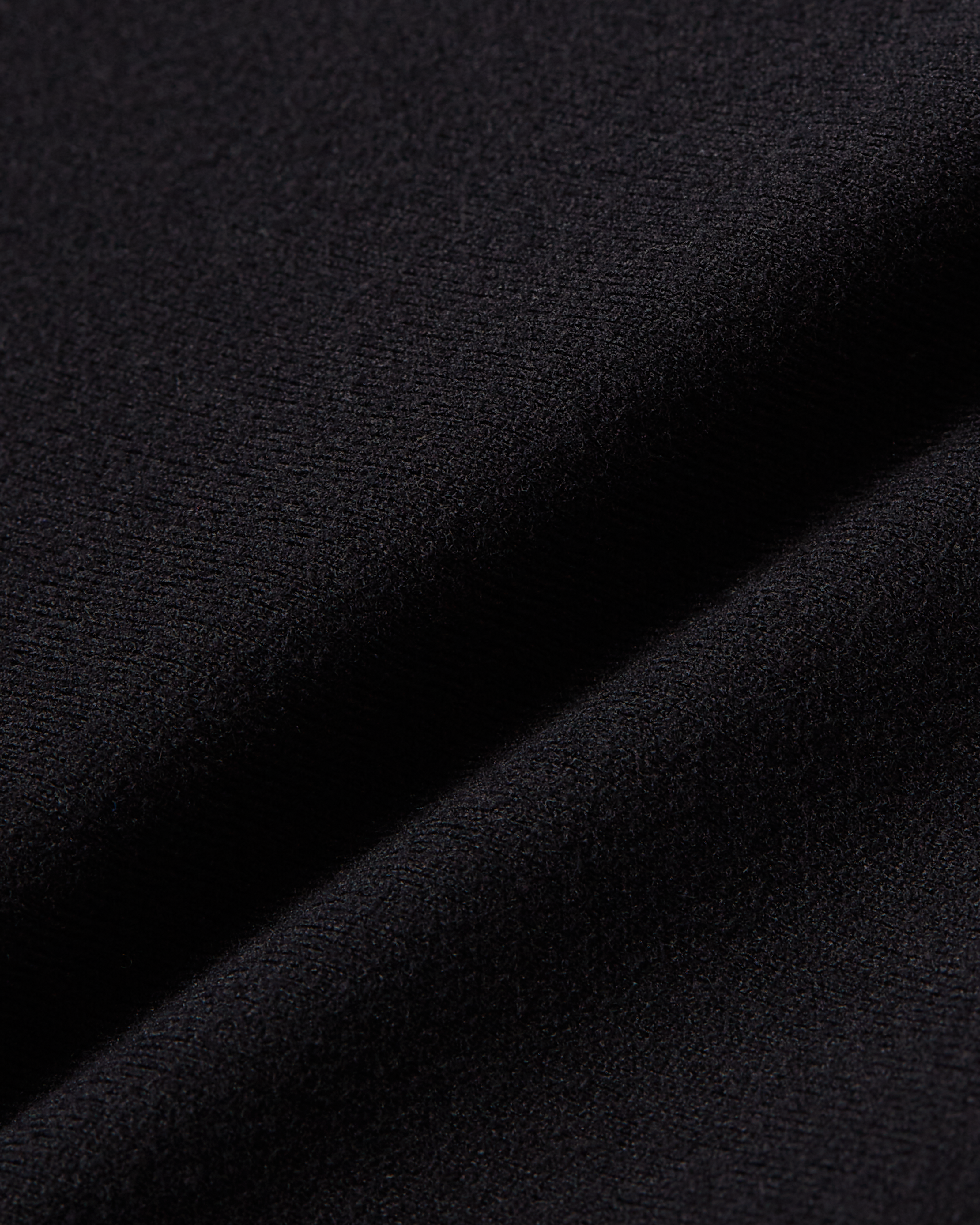 Close-up product photo of black soft skin fabric with dense smooth texture and stretch feel