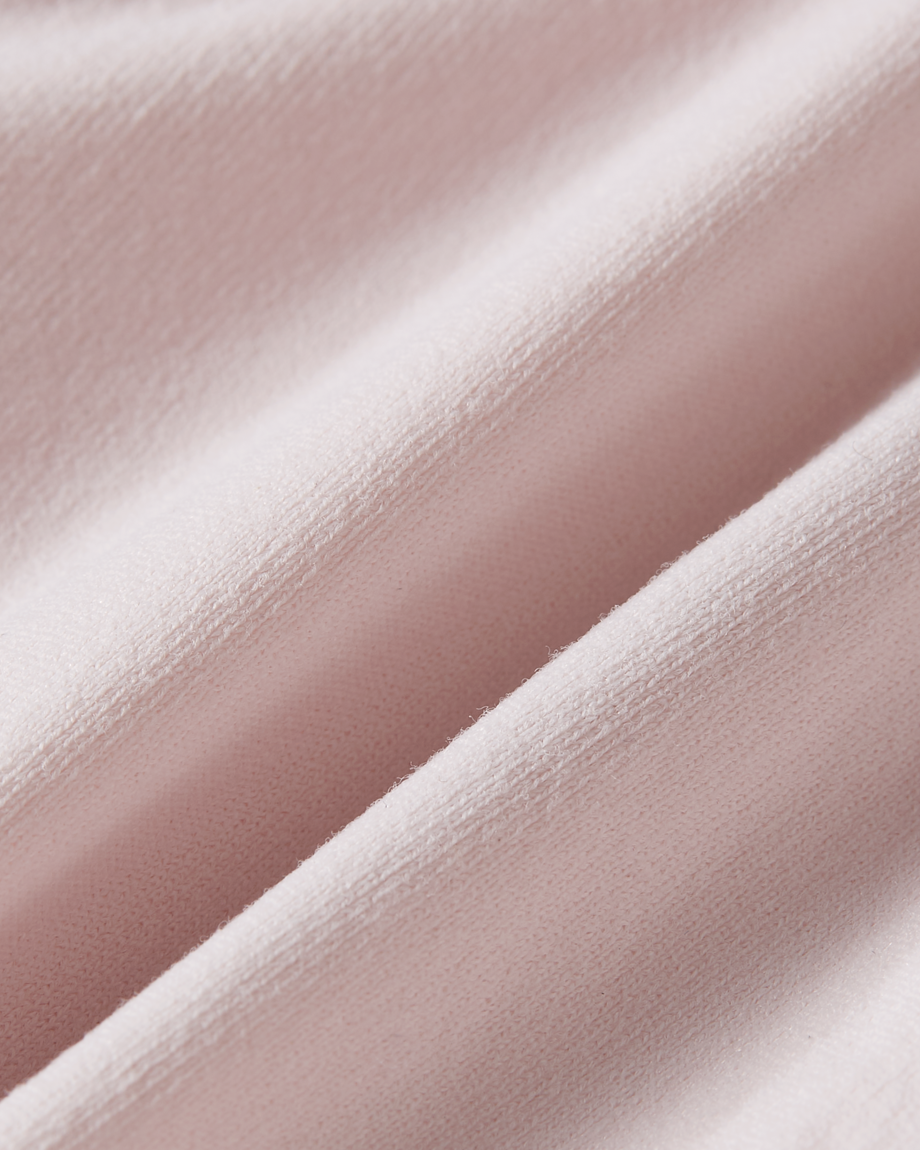 Close up of pink seamless bralette fabric showing a refined stretch texture that moves effortlessly with the body and feels soft to the touch