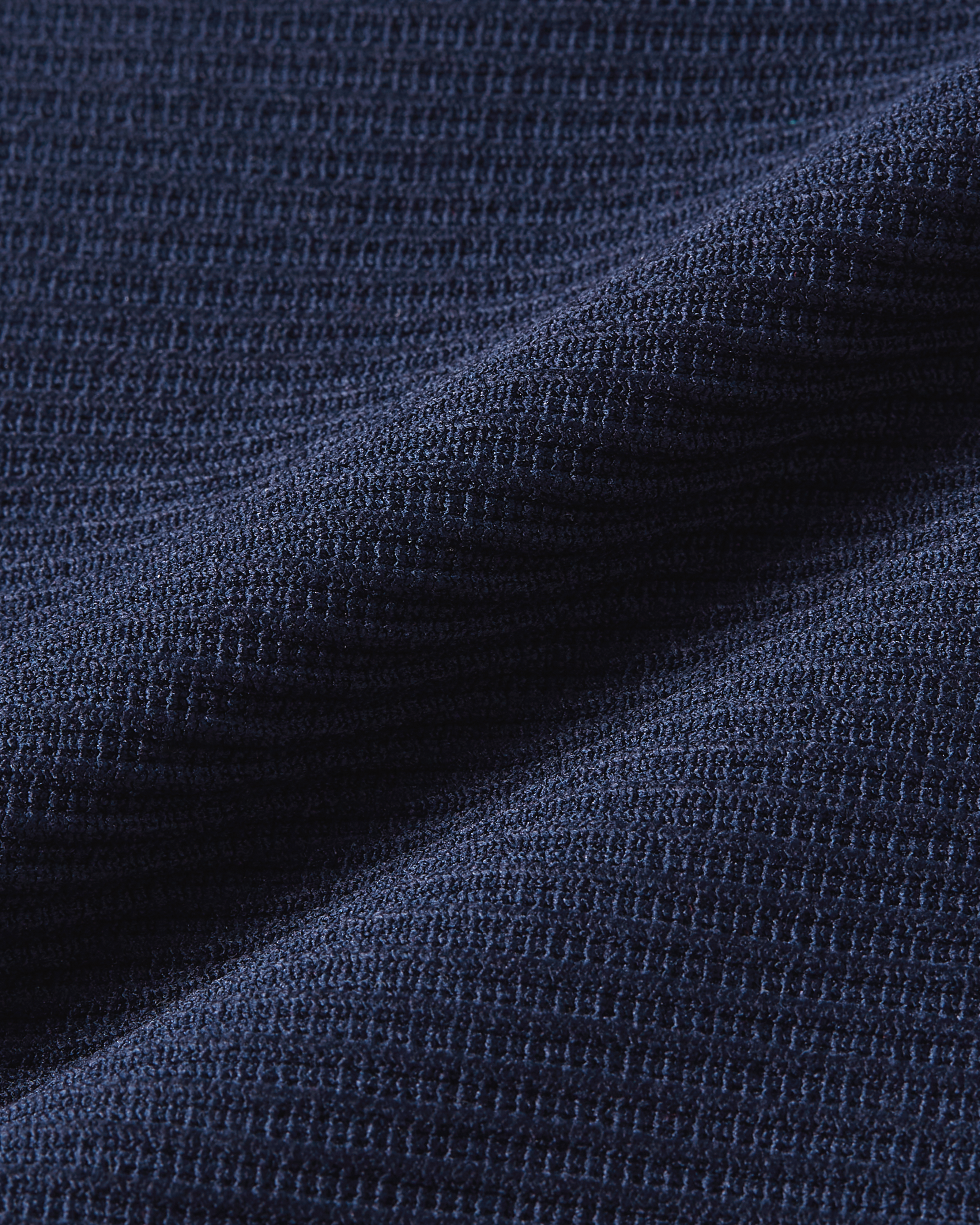 Detail product image of dark blue ribbed bodysuit fabric showing a structured texture with defined vertical lines and soft stretch
